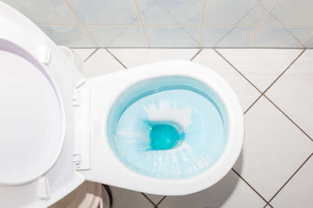 Cleaning and disinfection concept. White toilet bowl with blue detergent after flush.の写真素材