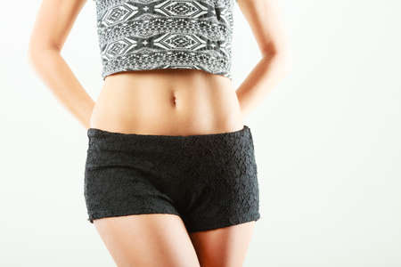 Closeup of sexy alluring woman hips and belly. Slim girl wearing black shorts shirtの写真素材