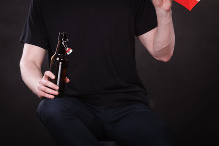 Addiction and trouble of drinking. Part body man with bottle of alcohol on dark background. Broken...