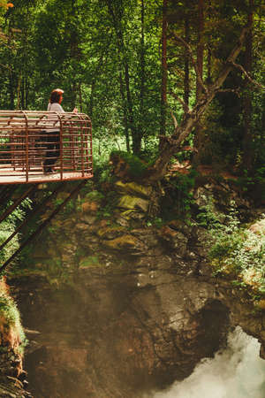 Tourist attraction in Norway, Europe. Woman photographer taking photo with camera on Gudbrandsjuvet viewpoint, Valldalen valley, between Valldal and Trollstigen.の写真素材