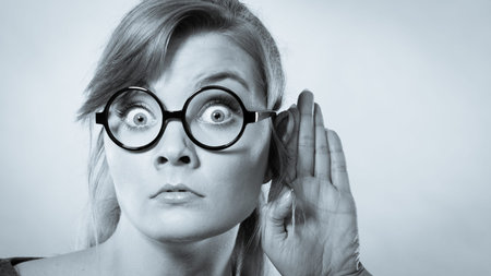 Hearing gesture shock emotion concept. Shocked girl eavesdropping. Young nerdy stunned lady in...