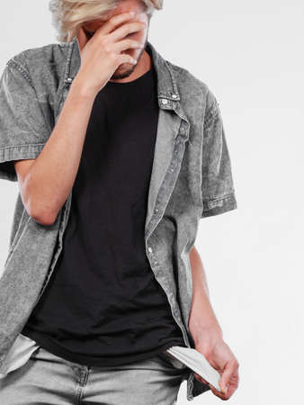 Financial difficulties, bad economy, no money concept. Young man male student showing empty pockets, sad unhappy face expressionの写真素材