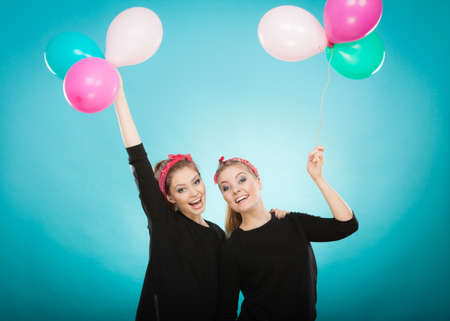 Memory of childhood and forgotten dreams. Two cute lovely retro styled women behave like little girls. Adults trying to fly away by balloons to dream come true.の写真素材