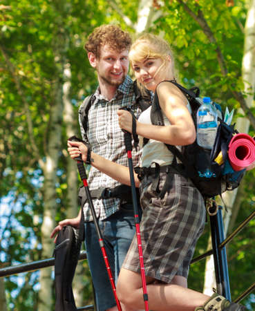 Two young people tourists hiking walking outdoor. Man and woman with trekking poles sticks.の写真素材