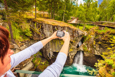 Tourist attraction in Norway, Europe. Woman photographer taking photo with camera on Gudbrandsjuvet viewpoint, Valldalen valley, between Valldal and Trollstigen.の写真素材
