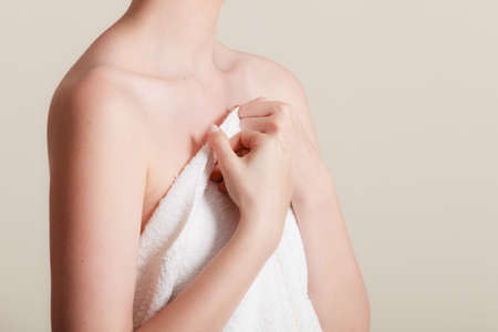 Shame and fear. Part body woman shamed of her nudity covering her breast with big bath towel. Innocence of female.の写真素材
