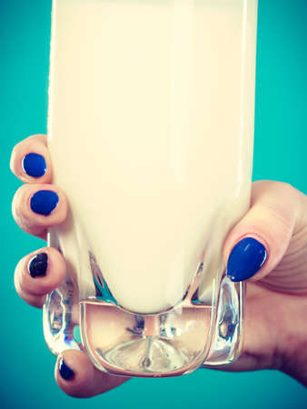 Healthy drinks, good nutrition, dairy products concept. Woman hand holding glass of milkの写真素材