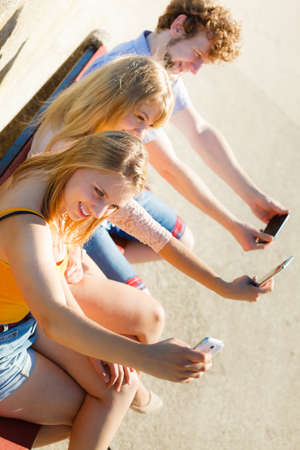 Friends taking selfie self photo picture with smartphone. Young women and man having fun outdoor. Summer relax.の写真素材