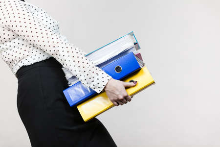 Woman holding many heavy colorful binders with documents. Office, bookkeeping objects concept.の写真素材