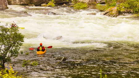 Scandinavian sports concept. People doing extreme white water mountain canoeing in rough river.の写真素材