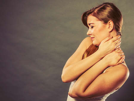 Feeling exhausted, back and spine disease. Woman having bad ache. Female placing hands on her neck suffering from painの写真素材