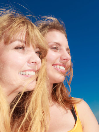 Two young women best friends blonde cheerful girls having fun outdoor against blue sky wind blowing...