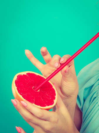 Healthy diet, refreshing food full of vitamins. Woman drinking juice from juicy fruit, red grapefruitの写真素材