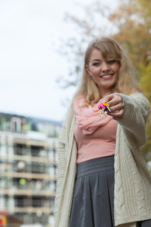 Real estate concept - young woman on front of new big modern house building construction site with keysの写真素材