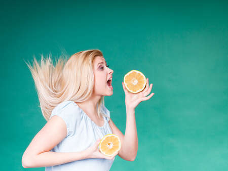Healthy diet, refreshing food full of vitamins. Woman with open mouth holding sweet delicious citrus fruit, orange grapefruit, she wants to take bite.の写真素材