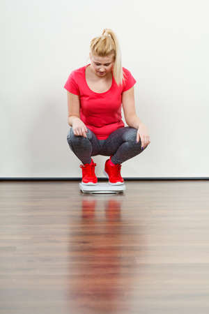 Healthy fit life style, controling body concept. Woman wearing sportswear, leggings and trainers standing on weight machine.の写真素材