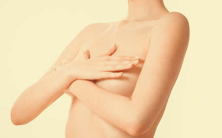 Health care, medicine, female controlling for cancer. Young topless woman covering her breast with handsの写真素材