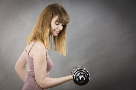 Young woman working out at home with heavy dumbbells. Training at home, being fit and healthy.