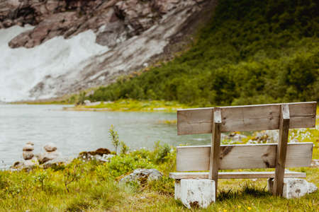 wooden bench at lake in norwegian mountain areaの写真素材