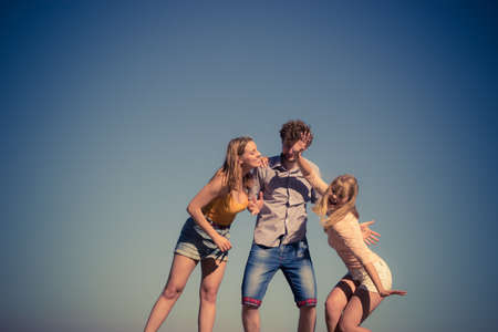 Friendship freedom summer holidays concept. Group of friends boy two girls spending time together having fun against skyの写真素材