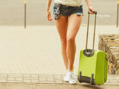 Travel and journey. Part body of female tourist traveller. Girl with green luggage suitcase baggage travelling visiting.の写真素材