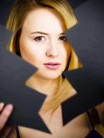 Depression, sadness, relationship problem concept. Young female with broken heart full of negative sad emotions. Woman covering her face by two parts of black love symbol.の写真素材