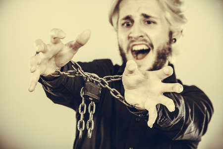 No freedom, social problems, human rights concept. Screaming furiously man with chained hands, studio shot on light grey backgroundの写真素材