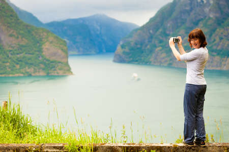 Tourism and travel. Woman tourist taking photo with camera, enjoying mountains fjords view in Sogn og Fjordane county. Norway Scandinavia.の写真素材