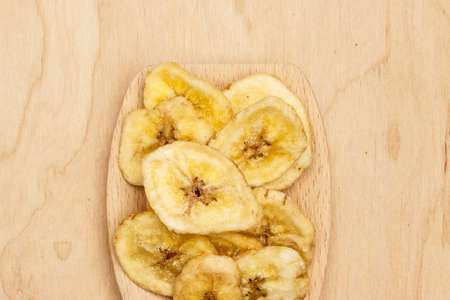 Heap of banana chips, dehydrated slices on wooden spoonの写真素材