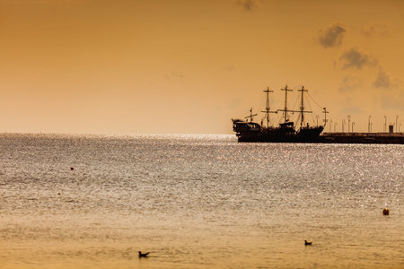 silhouette of an old sail pirate ship in the sea at the sunsetの写真素材