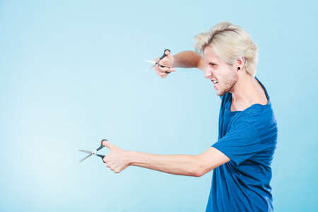 Haircut coiffure haircare concept. Passionate male hairdresser holding scissors showing work tools normal and thinning shearsの写真素材