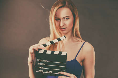 Woman holding professional film slate, movie clapper board. Hollywood production objects concept. Studio shot on black background.の写真素材