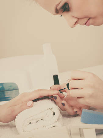 Closeup of beautician painting nails of female client. Woman in beauty spa salon doing manicureの写真素材