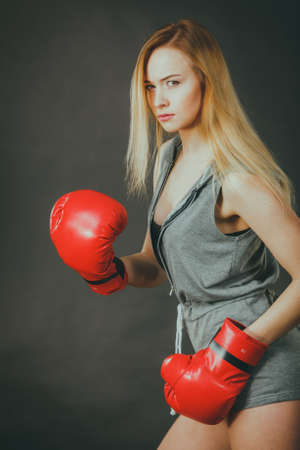 Young sensual woman, blonde attractive girl wearing red punch boxing gloves. Sport fitness and power concept.の写真素材