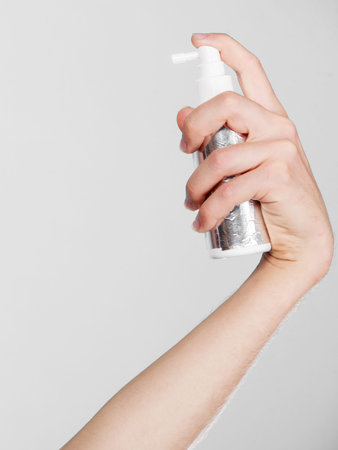 Hairdo haircare and makes hairstyle concept. Male hand holding spray cosmetic for hair, copy spaceの写真素材
