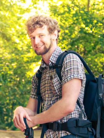 Adventure, tourism, enjoying summer time - young tourist man with backpack sticks hiking in forest trailの写真素材