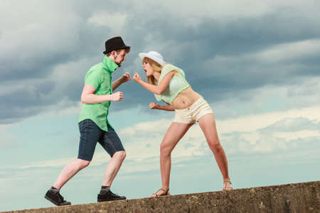 Relationship concept. Woman and man young hipster couple in love playing fighting outdoor on sky backgroundの写真素材
