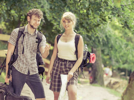 Man and woman tourists backpackers reading map on trip. Young couple hikers searching looking for direction guide. Backpacking summer vacation travel.の写真素材