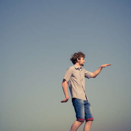 Young casual style man having fun outdoor against blue sky..の写真素材