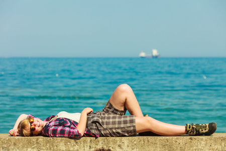 Summer vacation relax and traveling concept. Young tourist woman hiker relaxing on sea shore enjoying sunlightの写真素材