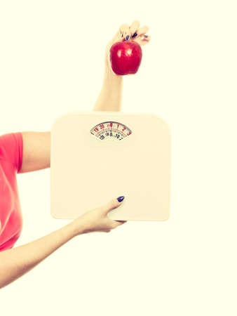 Healthy fit lifestyle, getting ready for diet concept. Woman hand holding red apple and weight machine.のeditorial素材