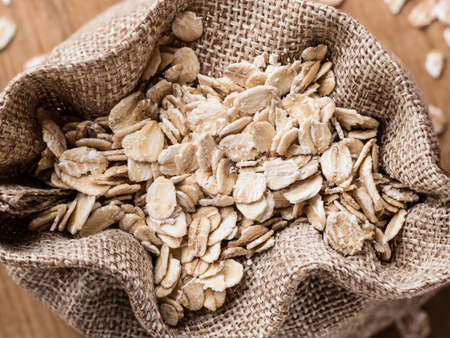 Dieting. Oat cereal in burlap sack on wooden surface, top, view. Healthy food for lowering cholesterol, protect heart.の写真素材