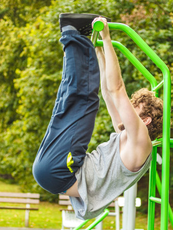 Active young man exercising on ladder. Muscular sporty guy in training suit working out at outdoor...