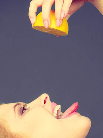 Healthy diet, refreshing food full of vitamins. Woman drinking juice from juicy fruit, yellow lemonのeditorial素材