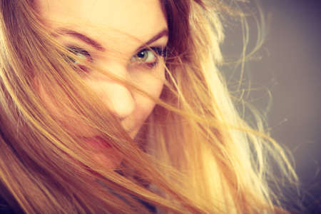 Haircare, beauty, hairstyling concept. Portrait of young attractive blonde woman wearing dark t shirt having windblown beautiful long hair on her face.のeditorial素材