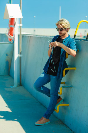 Contacts, technology concept. Young blonde man on vacations using his smartphone to check social...