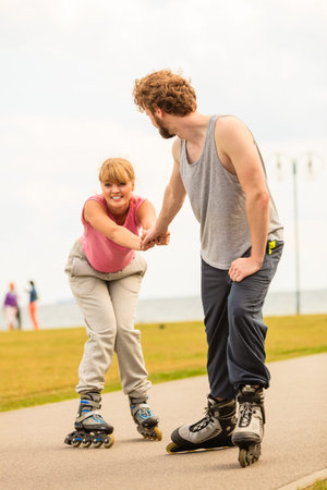 Active lifestyle people and freedom concept. Young fit couple on roller skates riding outdoors on...