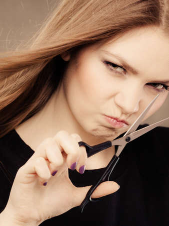 Craziness of professional hairdresser. Hair hygiene. Girl with scissors making crazy funny face preparing herself to cutting styling new image hairdo coiffure.の写真素材