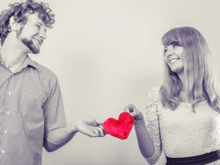 Romantic couple on valentines day. Happy joyful man and woman holding heart shape little pillow. Love concept.の写真素材