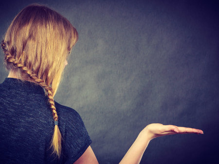 Hairstyles and hairstyiling concept. Woman with dark blonde hair and braid hairdo holding open hand,...